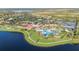Aerial view showcasing the community pool, tennis courts, clubhouse, lush greenery, and lake at 23590 Copperleaf Dr, Venice, FL 34293