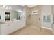 Bathroom featuring double sinks, white cabinetry, and a modern shower with glass doors at 23590 Copperleaf Dr, Venice, FL 34293