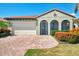 Inviting home with a red tile roof, arched entry, and lush landscaping along a brick driveway and a two car garage at 23590 Copperleaf Dr, Venice, FL 34293