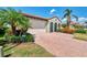 A well-manicured front yard with lush landscaping and a brick-paved driveway leads to the home's inviting entrance at 23590 Copperleaf Dr, Venice, FL 34293