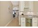 Open hallway with wine bar, beverage fridge, and marble countertop leading to kitchen at 23590 Copperleaf Dr, Venice, FL 34293