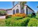 The arched entry and lush landscaping complement the well-maintained yard of the home with red tile roof at 23590 Copperleaf Dr, Venice, FL 34293