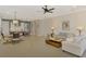 Open-concept living room flows into a dining area and kitchen, features tile flooring, ceiling fan, and decorative wainscoting at 23590 Copperleaf Dr, Venice, FL 34293