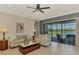 Bright living room features stylish decor, tile flooring, ceiling fan, and a sliding glass door with a view of the outdoor pool at 23590 Copperleaf Dr, Venice, FL 34293