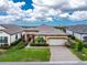 Front exterior featuring a two-car garage, stone accents, and manicured landscaping at 257 Corelli Dr, Nokomis, FL 34275