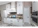 Close-up of the sleek kitchen featuring white cabinetry, tile backsplash, and stainless appliances at 257 Corelli Dr, Nokomis, FL 34275