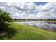 Scenic lake view from the property, with lush green lawn and surrounding houses under a bright blue sky with fluffy clouds at 257 Corelli Dr, Nokomis, FL 34275