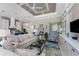 Open living space with custom shelving, a large TV, and views into the bright kitchen and dining areas at 257 Corelli Dr, Nokomis, FL 34275