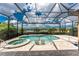 A screened in pool and spa with in-pool seating, lush landscaping, and lake views at 257 Corelli Dr, Nokomis, FL 34275