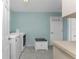Well-lit laundry room features tile flooring, front-load washer and dryer, and storage bench at 2673 Titania Rd, Englewood, FL 34224