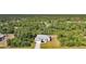 Aerial view of light yellow home with metal roof in a verdant, tropical setting at 2957 Montgomery Dr, Port Charlotte, FL 33981