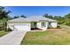 Aerial view of a light yellow home with metal roof, well-maintained lawn, and a two-car garage at 2957 Montgomery Dr, Port Charlotte, FL 33981