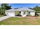 Aerial view of a one-story home with a light-colored exterior, metal roof, well maintained lawn, and two-car garage at 2957 Montgomery Dr, Port Charlotte, FL 33981