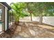 Spacious fenced backyard with mature trees and landscaping, featuring an extended screened lanai and mulched flowerbeds at 3593 Birmingham Ln, North Port, FL 34288