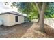 Fenced backyard with a mix of grass, mulch, and a screened lanai on a sunny day under a scattering of trees at 3593 Birmingham Ln, North Port, FL 34288
