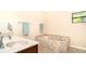 Spacious bathroom featuring a marble encased bathtub, double sinks, and natural light from an external window at 3593 Birmingham Ln, North Port, FL 34288