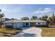 Charming single-story home featuring a well-manicured lawn, and a stone accent wall and a driveway that leads to an attached garage at 360 E Wentworth Cir, Englewood, FL 34223