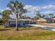 Single-Gathering home featuring mature palm trees, stone accents, and a concrete driveway at 360 E Wentworth Cir, Englewood, FL 34223