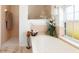 Bright bathroom features a soaking tub with shower, window, flowers, and decorative details at 39 Medalist Ln, Rotonda West, FL 33947