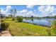 Scenic backyard view with lush green lawn extending to a tranquil lake under a beautiful sky at 4115 Hemingway Dr, Venice, FL 34293