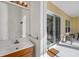 Bathroom with single sink vanity, wood cabinets, and sliding doors leading to an outdoor living area at 4115 Hemingway Dr, Venice, FL 34293