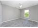 A cozy bedroom with wood-look tile flooring, a ceiling fan, and a window for natural light at 5273 Gillot Blvd, Port Charlotte, FL 33981