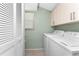 Practical laundry room complete with washer, dryer, overhead cabinets, and a closet for storage solutions at 6796 Gasparilla Pines Blvd # 63, Englewood, FL 34224