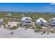Aerial view showcasing a stilted beach house, surrounded by lush vegetation and pristine white sands at 6890 Palm Island Dr, Placida, FL 33946