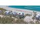 Aerial view of elegant beachfront homes with white metal roofs and manicured landscaping against a backdrop of turquoise ocean waters at 6890 Palm Island Dr, Placida, FL 33946