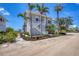 A beautiful two-story beach house features meticulous landscaping, mature palms, and intricate lattice design at 6890 Palm Island Dr, Placida, FL 33946