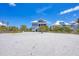 Charming beach house with a light exterior, elevated on stilts with palm trees and a sandy beach at 6890 Palm Island Dr, Placida, FL 33946
