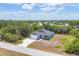 Aerial view of a charming blue single-Gathering home with an attached garage, lush landscaping, and a long driveway at 7332 Brandywine Dr, Englewood, FL 34224