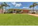 Inviting home with a green lawn, mature palm trees, and a spacious driveway leading to the attached garage at 8180 Burwell Cir, Port Charlotte, FL 33981