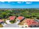 An aerial shot shows a home with a red tile roof, surrounded by mature trees and manicured lawns at 8320 Creekview Ln, Englewood, FL 34224