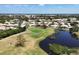 Aerial view of a pristine golf course and serene pond at 8320 Creekview Ln, Englewood, FL 34224