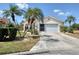 Charming single-story home with a two-car garage, tile roof, and beautiful landscaping including palm trees at 8320 Creekview Ln, Englewood, FL 34224