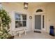 Welcoming front porch with elegant light fixture, window, bench, and a decorative wreath on the door at 8320 Creekview Ln, Englewood, FL 34224