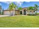 Charming home featuring a spacious three-car garage, lush landscaping, and manicured lawn at 8400 Antwerp Cir, Port Charlotte, FL 33981