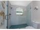 Shower features glass doors, light blue tiling, and a window providing natural light at 875 Morrison Ave, Englewood, FL 34223