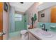 Bright bathroom featuring vintage green tiling, a shower with window, and a pedestal sink at 875 Morrison Ave, Englewood, FL 34223