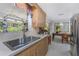 Bright kitchen featuring a sink with a garden window overlooking the greenery and a view to the dining area at 875 Morrison Ave, Englewood, FL 34223