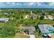 An aerial view of the home showcasing a pool, mature landscaping, a driveway, and a two-car garage at 9211 Koma St, Port Charlotte, FL 33981