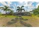 Lush backyard featuring a screened-in pool, green grass, and swaying palm trees, perfect for outdoor relaxation at 9211 Koma St, Port Charlotte, FL 33981