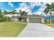 Well-maintained home with an attached garage, lush lawn, and mature tropical landscaping at 9211 Koma St, Port Charlotte, FL 33981