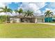 Beautiful single-story home featuring mature palm trees and a meticulously maintained lawn at 9211 Koma St, Port Charlotte, FL 33981