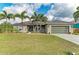 Charming single-story home with mature palm trees, lush green lawn, and a welcoming front porch at 9211 Koma St, Port Charlotte, FL 33981