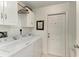 Bright laundry room with white washer, dryer, cabinets, and access door at 9211 Koma St, Port Charlotte, FL 33981