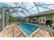Large, screened-in pool with brick patio and seating area at 9211 Koma St, Port Charlotte, FL 33981
