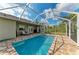 Screened-in pool with brick patio and seating and manicured yard at 9211 Koma St, Port Charlotte, FL 33981