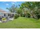 Spacious backyard with a patio, lush lawn, privacy wall, and mature trees for a serene outdoor setting at 1 Curacao Cir # 44, Englewood, FL 34223